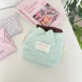 Detalle de bolsa de cordón acolchada con corazones verde menta para cosméticos en el escritorio - Verde