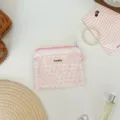 Gros plan d'une pochette fleurie rose avec bordure en dentelle blanche et fermeture éclair - Point Floral Rose