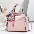 Dettaglio della borsa rosa con foulard in seta stampato elegante e finiture metalliche lucide. - Rosa
