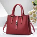 Red structured tote bag detail, featuring textured chevron pattern and secure metal lock closure. - Wine Red