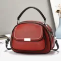 Nahaufnahme der roten Handtasche aus Kieselleder mit weißen Nähten und Silberbeschlägen - Rot