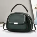 Detailansicht einer grünen Handtasche mit Doppeltaschen, Strukturleder und Tragegriff. - Grün