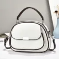 Detailansicht einer eleganten weißen Handtasche mit braunem Rand und Silberschnalle. - Gebrochenes Weiß