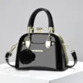 Borsa a conchiglia in pelle verniciata nera con dettagli dorati e ciondolo floreale elegante. - Nero