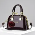 Borsa a mano a conchiglia in pelle verniciata con ciondolo a rosa rossa e dettagli dorati. - Viola scuro