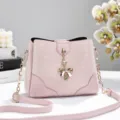 Pink bucket bag with bow pendant, stylish printed design and gold chain strap for women. - Pink