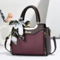 Detailed view of women fashion tote handbag with elegant printed silk scarf and metallic logo. - Coffee & Red