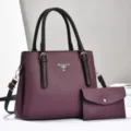Close-up view showing the textured purple leather and metallic logo detail of the bag. - Purple
