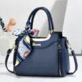 Stylish women's dark blue shoulder tote bag with silk scarf accessory and metal details. - Blue