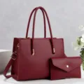 Detail view of the stylish wine red leather tote bag with matching clutch purse and hardware accents. - Red