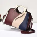 Stylish color-block women shoulder handbag with unique metal cat tail handle design. - Wine Red