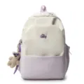 Close-up detail view of the cute bear plush pendant and embroidered letter on the backpack. - Purple