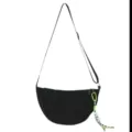Close-up detail of black nylon crescent dumpling shoulder bag with adjustable strap and charm. - With Pendant / Black