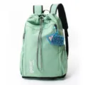 Détail de sac à dos cordon vert clair montrant broderie avant et accessoire porte-clés. - Vert
