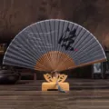 Vue détaillée d'un éventail pliant chinois traditionnel en lin avec support en bois. - Frais