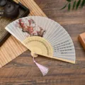 Traditional Chinese folding fan with plum blossom and calligraphy, wooden frame, pink tassel. - Style 5 (Winter Plum)