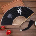 Chinese style folding fan with black fabric, wooden ribs, Zen calligraphy and tassel. - 06 Zen