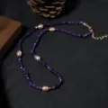 Nahaufnahme der lila Perlenkette mit rosa Perlen und goldenen Details vor dunklem Hintergrund. - Amethyst Perlen Set Halskette