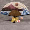Éventail pliant en soie classique avec support en bois et pompon, design paysager élégant. - Soleil Levant Or