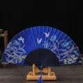 Traditional Chinese style folding fan with blue floral and butterfly pattern on wooden stand. - No. 7 Blue Ribs & Blue Face (Lily)