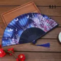 Vue détaillée du éventail pliant traditionnel avec motif papillon floral et pompon. - A11