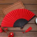 Ventaglio pieghevole in pizzo rosso con stecche intagliate nere e nappa per feste e matrimoni. - Stile H