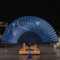 Traditional Chinese folding fan with linen fabric surface, elegant orchid pattern and wooden stand. - No. 6 Orchids