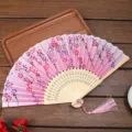 Ventaglio pieghevole tradizionale con motivo floreale rosa, struttura in bambù e nappa. - A07