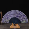 Japanese style folding fan with purple floral butterfly pattern, wooden stand and tassel decor. - No. 10 Blue Ribs & Purple Face (Lily)