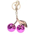 Nahaufnahme des glänzenden lila Kirschen-Taschenanhängers mit goldenem Ring und Blatt. - Gold + Violett