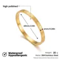 Vista detallada de pulsera rígida de acero dorado con grabado de corazones y brillo pulido. - Brazalete de Corazón