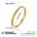 Vista detallada de pulsera rígida en acero dorado, con acabado brillante y diseño de hojas finas. - Brazaletes calados de pétalos ovales con estrás