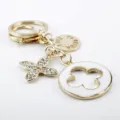 Portachiavi dorato con fiori trifoglio in strass, elegante accessorio per borsa. - Bianco