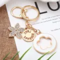 Portachiavi in lega d'oro con ciondolo a fiore a cinque petali in strass e ciondolo per borsa. - Bianco