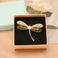 Gold dragonfly brooch with shimmering crystals and a central pearl in a delicate gift box. - Dragonfly Design