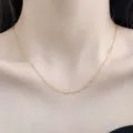 Detailaufnahme einer zarten, goldfarbenen O-Kette, die elegant am Hals getragen wird. - Ankerkette / Gold