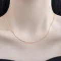 Nahaufnahme einer zarten goldfarbenen Box-Kette, die elegant und stilvoll am Hals getragen wird. - Venezianerkette / Vergoldet