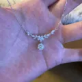 Close-up detail shot of the sparkling zircon floral necklace displayed neatly on a palm. - 925 Silver / White Gold