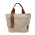 Dettaglio di borsa a secchiello in tela con corpo beige, manici marroni e tasca frontale. - Kaki