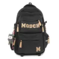 Detailed view of the black student backpack featuring MGDCH letters and cute plush charm. - Black
