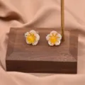 Exquisite Blumen-Ohrstecker mit weißen Muschelblüten und leuchtend gelben Steinmitteln. - Bernsteingelber Stil