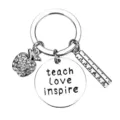 Detailed close-up of teacher metal keychain with rhinestone apple and engraved inspiration charm. - Teacher Style