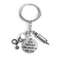 Detailed close-up of a silver medical keychain featuring a stethoscope, syringe, and engraved tag. - She Believed Style