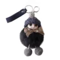 Detailed view of cute plush doll keychain featuring a fluffy black pompom and grey knitted hat - Black