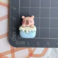 Primer plano de detalles de dijes de resina de animales lindos para manualidades de fundas. - Capibara Rollo de Pastel Azul