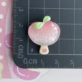 Close-up of sparkly pink peach resin charm with green leaves, perfect for DIY crafts and jewelry. - Pink Peach Popsicle