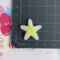 Gros plan détaillé d'un cabochon en résine d'étoile de mer jaune scintillante pour bricolage. - Étoile De Mer Dégradée À Paillettes Jaune