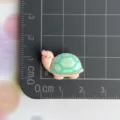 Detailansicht des Harz-Schildkröten-Anhängers, süßes rosa-grünes Meereskreaturen-DIY-Zubehör. - Grüne Schildkröte mit Blume