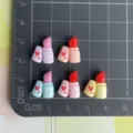 Primo piano dettaglio di cabochon in resina mini rossetto con stampa per decorazioni fai-tec. - Rossetto Cuore (Misto Casuale)