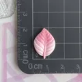Vista de cerca de un accesorio de resina en forma de hoja rosa con detalles finos y venas muy claras. - Hoja Degradada Rosa
